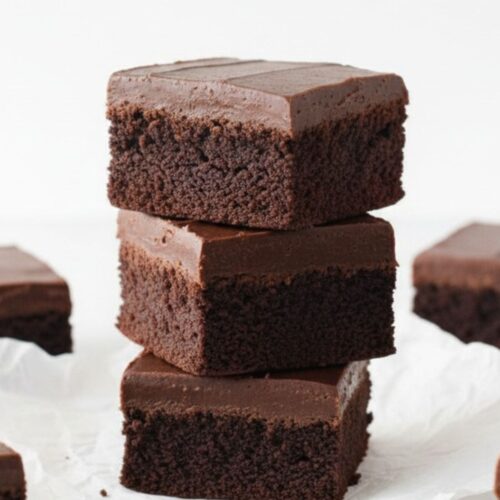 : Rich Nutella Fudge Brownies sliced into squares showing three chocolate layers on white marble surface