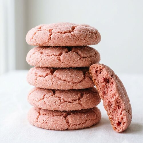 Stack of soft pink strawberry sugar cookies rolled in sugar on a white background